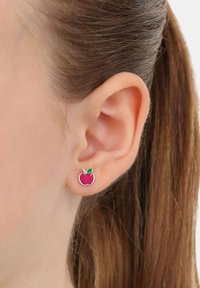Orecchino a forma di mela d'argento con smalto rosso glitterato, un accento di foglia verde e una finitura lucida, esposto su uno sfondo neutro.