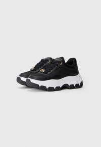 Sneaker nere con suola bianca spessa, dotate di tomaia in pelle liscia, occhielli dorati e dettagli con logo sulla linguetta.