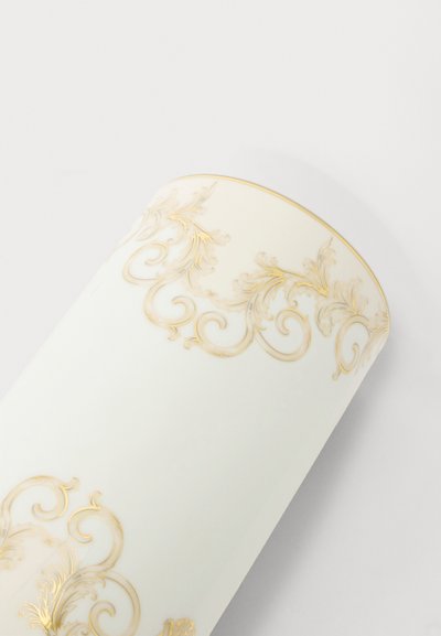 Vase en céramique blanche avec des motifs floraux dorés ornementaux près des bords supérieur et inférieur sur un fond clair.