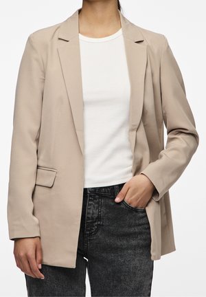 Beige blazer met een notch-revers, enkele knopen sluiting en een gladde textuur; gedragen over een witte ribbeltop en zwarte jeans.