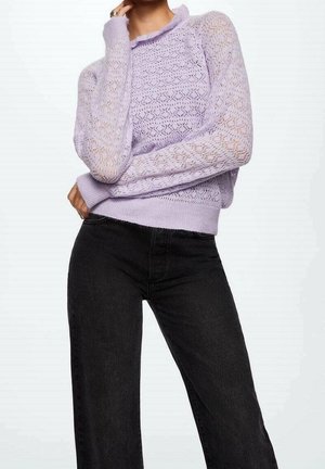 Maglione lavorato a maglia lilla con motivo testurizzato e scollatura con volant, abbinato a jeans neri in denim a vita alta, entrambi con maniche lunghe.