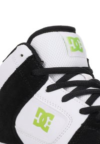 Zwart-wit skateschoen met een bovenwerk van mesh, suède accenten, groen logo en zwarte veters. Beschikt over een gevoerde enkel voor ondersteuning.