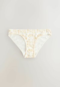 Sous-vêtement style bikini blanc avec un motif floral et végétal jaune sur un fond clair uni.