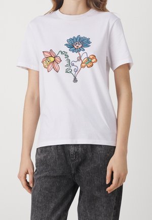 White short-sleeve shirt with colorful cartoon-style flowers, one wearing sunglasses, worn with black washed jeans.