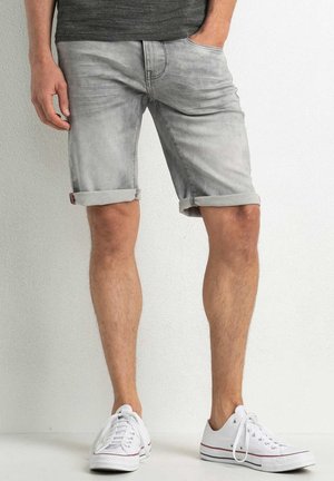 Graue Jeansshorts mit umgeschlagenen Säumen, fünf Taschen und leichtem Verblassen, kombiniert mit weißen Sneakern mit grauen Akzenten und Schnürsenkeln.