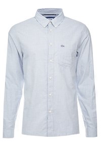 Světle modrá košile s dlouhým rukávem v kostkovaném vzoru, s límečkem na knoflíky, přední kapsou a vyšívaným logem na hrudi.