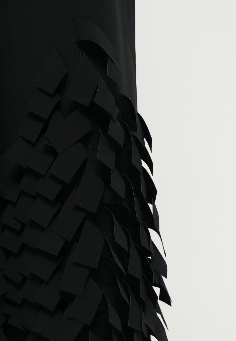 Zwarte kledingstukken met gelaagde, gebogen stofstrips die een gestructureerd, gerimpeld effect langs de zoom creëren. Glad bovenste gedeelte, gestroomlijnd ontwerp.