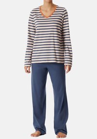 Randig långärmad topp i kräm och marinblå, med en V-utrigning och orange kant. Kombinerad med enhetliga marinblå pyjamasbyxor. Mjuk tyg.