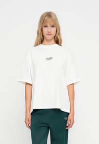 Tricou alb supradimensionat din bumbac, cu mâneci scurte și guler rotund. Logo-ul verde centrat adaugă detalii.