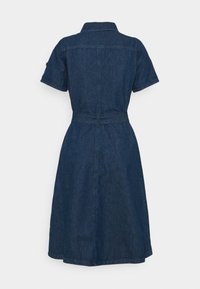 Mörk denimklänning med krage, korta ärmar, midjeband och en utsvängd kjol. Har en sömlös bakdesign och en fåll precis ovanför knäna.