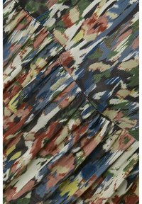 Tissu à motifs floraux avec des plis. Les couleurs incluent le vert, le bleu, le rouge et le jaune sur un fond clair. Surface texturée avec des détails en maille.