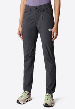 Donkergrijze technische wandelbroek met ritszakken en het The North Face-logo op het bovenbeen, gedragen met meerkleurige trailrunning schoenen.