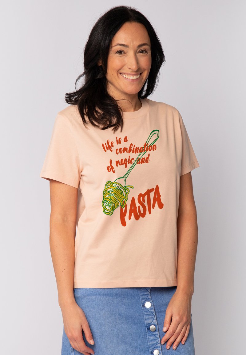 Perzikkleurig katoenen T-shirt met een afbeelding van pasta op een vork. De tekst luidt "het leven is een combinatie van magie en PASTA" in rood en groen.
