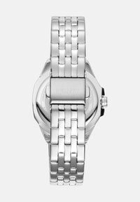 Montre en acier inoxydable argenté avec un bracelet à maillons, présentant un boîtier rond et une finition polie. Le nom de la marque est gravé sur le fermoir.