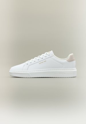 Valged madala säärega tennised paeladega, beež kontsaklapp ja "GAP EST. 1969" kuldsed tähed küljel ja tallal, neutraalse tausta vastu.