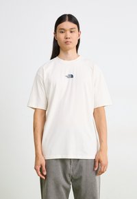 Lys beige T-skjorte med korte ermer og rund hals. Har en liten logo foran i mørkegrønn. Laget av mykt bomullsmateriale.
