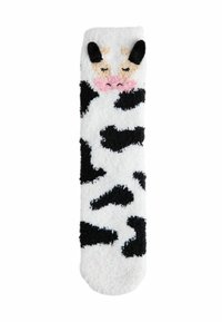 Vit fluffig strumpa med svarta fläckar som liknar en ko, med ett broderat kohuvud med öron och en rosa nos nära toppen. Mjukt material genom hela strumpan.