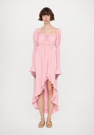 Lys rosa, off-shoulder kjole med lange, smockede ærmer, rynket kant og høj-lav snit, parret med gule sandaletter med stropper.