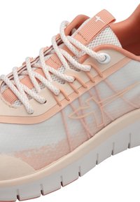 Zapatos deportivos ligeros con parte superior de malla en crema y rosa pastel, suela acolchada y detalles texturizados en el lateral.