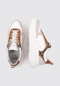Sneakers bianchi e beige con accenti in stampa zebrata, materiali in suede e pelle, suole bianche spesse e lacci marroni. Logo del marchio visibile all'interno.