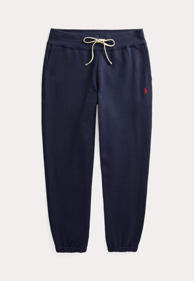 Marineblauwe joggerbroek met elastische boorden, witte aantrekkoord in de taille, zijzakken en klein rood geborduurd logo op de linker dij.