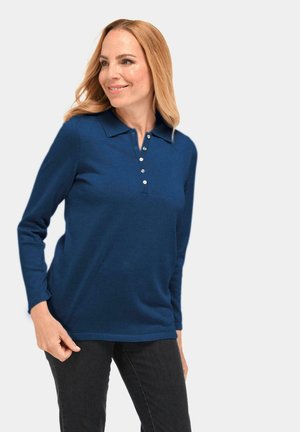 Dunkelblaues Langarm-Polohemd mit Kragen, mit einer Knopfleiste und geripptem Muster. Kombiniert mit dunklen Jeans.