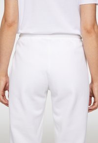 Vita sweatpants med en mjuk textur, elastisk midjeband och avslappnad passform. Enkel design utan mönster eller synlig hårdvara.