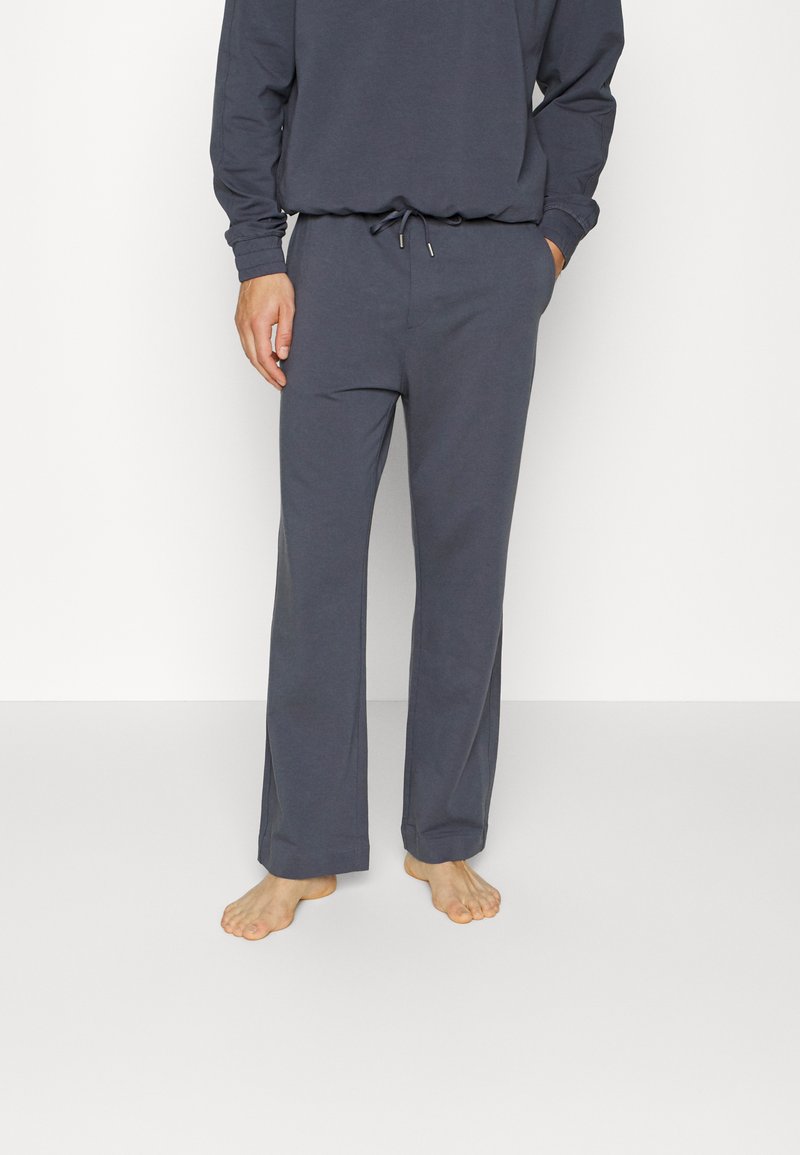 Conjunto de roupa de estar em algodão leve e cinza, com uma blusa de manga longa e calças com cordão ajustável, de corte solto e textura suave.