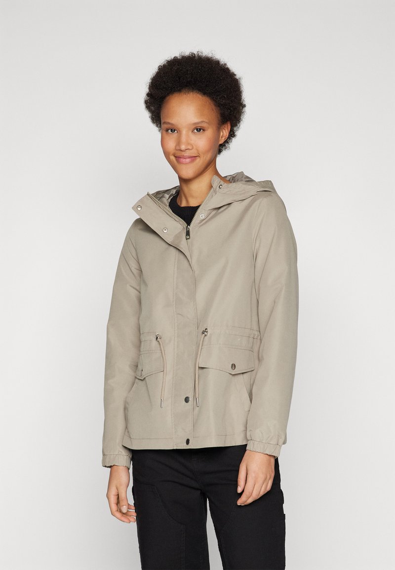 Beige lett jakke med hette, snøring i midjen og to frontlommer; glatt tekstur med et uformelt design og elastiske mansjetter.