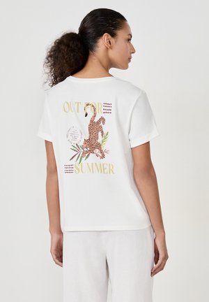 T-shirt en coton blanc à coupe décontractée, avec un graphique de léopard coloré et le texte "SORTIE POUR L'ÉTÉ" au dos. Manches courtes.