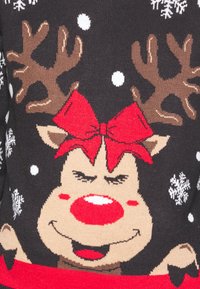 Svart stickad tröja med en ren som har en röd rosett, ett leende ansiktsuttryck, vita snöflingor och röda detaljer.