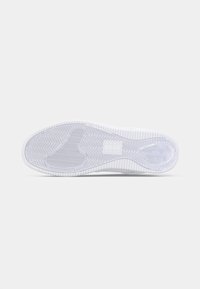 Semelle de chaussure blanche avec un motif en chevrons, des rainures texturées et des détails de logo. Matériau en caoutchouc lisse, design plat pour la traction.