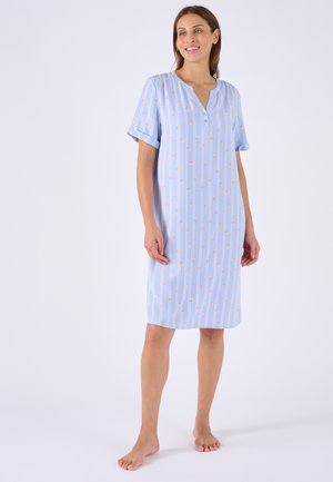 Femme debout pieds nus portant une robe bleu clair longueur genou avec des manches courtes et un motif à rayures verticales florales.