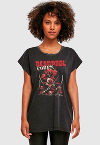 Must piss suurusega must T-särk lühikeste varrukatega, millel on grafitiprint Deadpoolist ja "DEADPOOL CORPS" punases tekstis. Pehme kangas, vintage stiil.