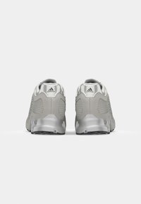 Zapatillas deportivas grises con detalles de malla, cuello acolchado en el tobillo y suela de goma texturizada. Presentan un branding minimalista en el talón.