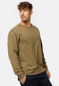 Langärmliges Shirt mit Rundhalsausschnitt in olivgrün, aus strukturiertem Stoff mit einem subtilen Karomuster, gerippten Bündchen und einem lässigen Schnitt.
