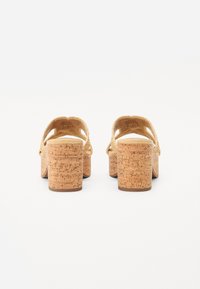 Kork-Plateau-Absätze mit einem geflochtenen Riemen-Design. Der Schuh verfügt über eine strukturierte Kork-Oberfläche und einen stabilen Blockabsatz für Unterstützung.