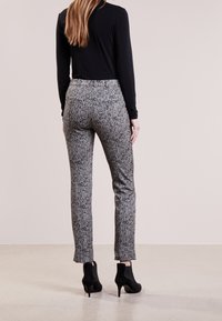 Šedé houndstooth slim-fit kalhoty s mírným vzestupem, s hladkou texturou a postranními kapsami, doplněné černými kotníkovými botami.