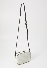 Borsa a tracolla con una texture bianca screpolata, forma rettangolare, tracolla nera regolabile e accenti in oro.