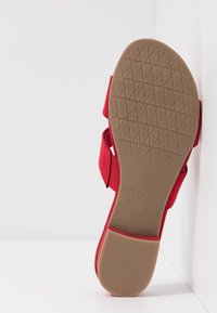 Sandale en tissu rouge avec des sangles réglables, semelle plate et semelle en caoutchouc texturé. Taille 37 imprimée sur le dessous.