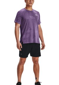 Lila Sport-T-Shirt mit strukturiertem Muster und kurzen Ärmeln, kombiniert mit schwarzen Shorts. Beide Teile zeigen das Under Armour Logo.