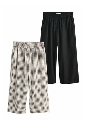 Twee paar cropped broeken met elastische taille, één effen zwart en één zwart-wit geruit, plat uitgespreid op een witte achtergrond.