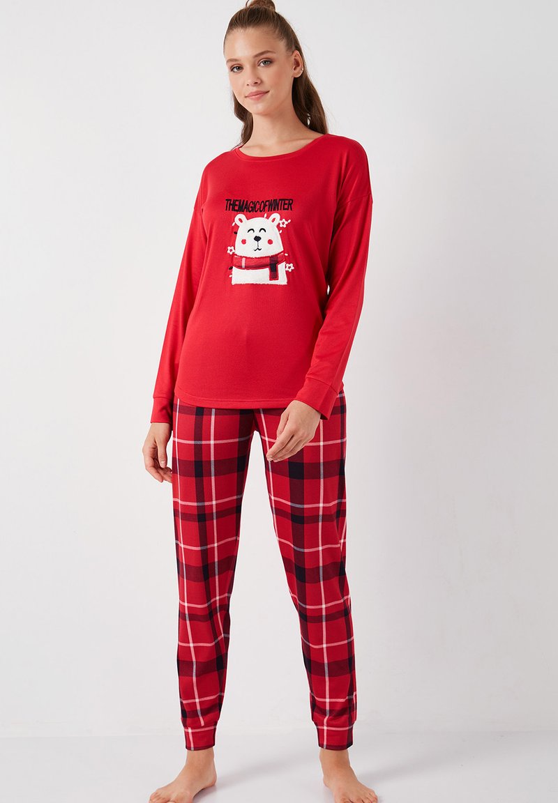 Punainen pitkähihainen pyjamapaita, jossa on jääkarhun grafiikka ja teksti, yhdistettynä punamustaruutuisiin pyjamahousuihin, jotka ovat valmistettu pehmeästä materiaalista.