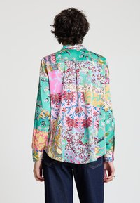 Long-sleeve, multicolored shirt featuring a mix of floral and geometric patterns, silky texture, and a collared neckline. Curved hem at the back.