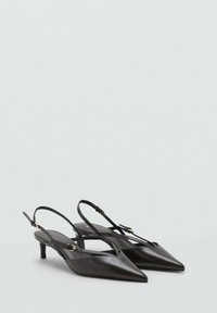 Musta teräväkärkinen slingback-korkokenkä, jossa on ohuet hihnat ja pieni kultainen solki vaaleanharmaalla taustalla.