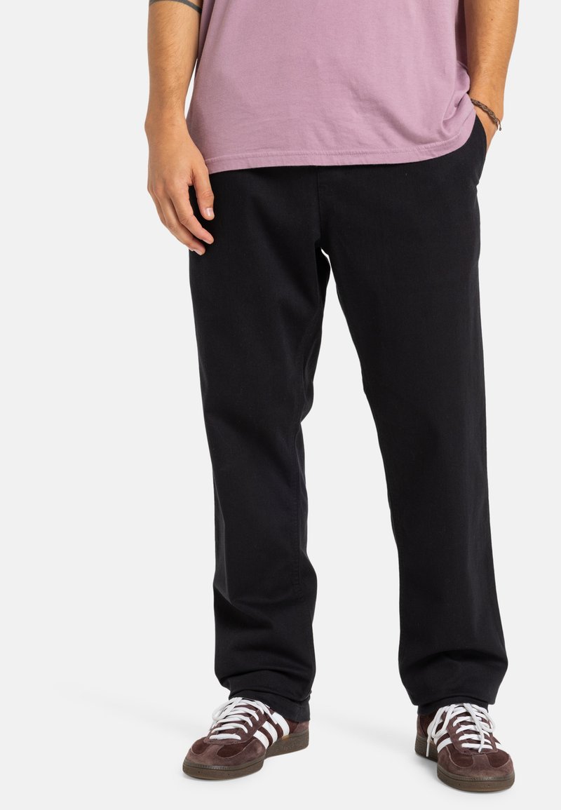 Čierne bavlnené nohavice so strihom rovn�ého nohu, majú bočné vrecká a sú skombinované s gaštanovými teniskami s bielymi akcentmi.