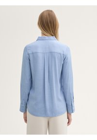 Camicia a maniche lunghe azzurro chiaro con colletto, cucitura della spalla posteriore e polsini con bottone. Realizzata in un tessuto morbido e testurizzato.