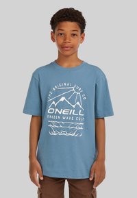 Camiseta de algodón azul con mangas cortas; presenta gráficos impresos en blanco de montañas y olas, y texto que dice "O'Neill Frozen Wave Cult."
