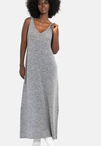 Długa szara dzianinowa sukienka z głębokim dekoltem w kształcie litery V i bez rękawów, o miękkiej fakturze i luźnym kroju.