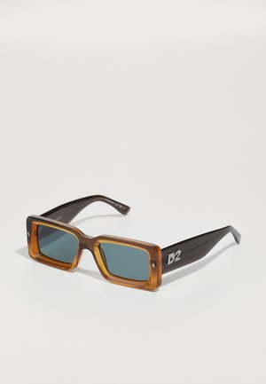 Brown-tinted rectangular sunglasses with green lenses. Thick, transparent frames with a dark brown arm featuring a silver "D2" logo.